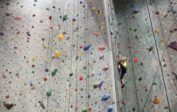 Young girl climbing to the top of a climbing rock wall