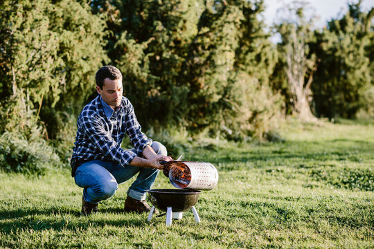 Young man pouring hot cole into barbecue