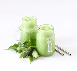 Vegetable smoothie of cucumbers and mint in a jar with a bamboo straw on a light background