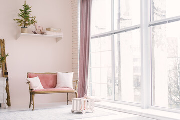 A pink vintage sofa with pillows stands near the window in the living room or children's room, decorated for Christmas or New Year, in the house. Minimalistic interior design