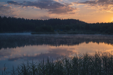 Fototapeta premium Summer landscape of Belarus. Beautiful sunrise over the lake. Reflections of clouds on the water.