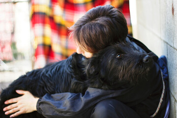 Portrait of woman hugging a giant Schnauzer dog looking at the camera