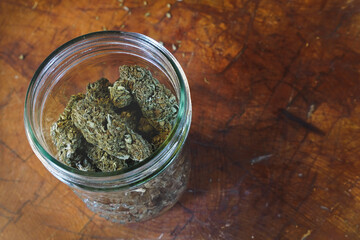 Dried Cannabis with jar and wood background  