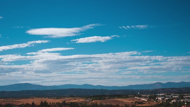 Timelapse of white clouds on a blue clear sky at morning over the mountains. 