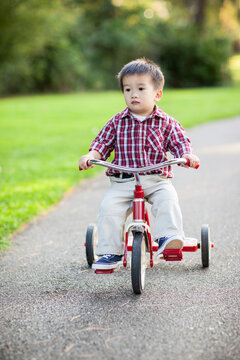 Asian kid riding a tricyle outdoor