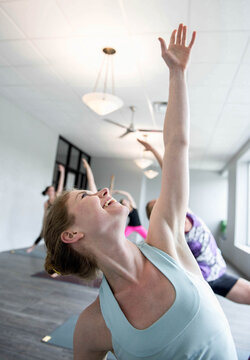 Woman smiles as she assumes a posture during a yoga class