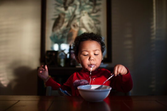 toddler boy eats cereal for breakfast