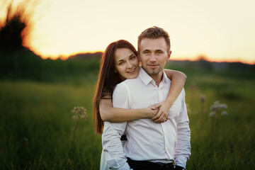 young couple in love are hugging outdoors in the field at sunset on summer day. Romantic, love, people concept. love story