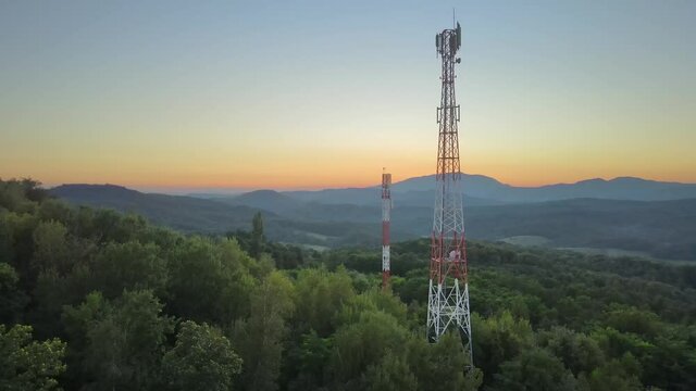 5G cellular mobile transmission towers on hillside, sunset aerial panorama