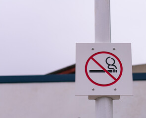 Señal de prohibido fumar sujeta en un poste blanco
