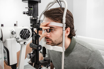 Adult man eyesight test with binocular slit-lamp. Checking retina of a male eye close-up....