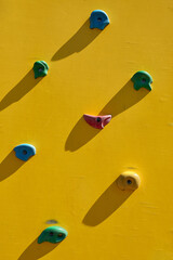 Yellow climbing wall with colorful rocks