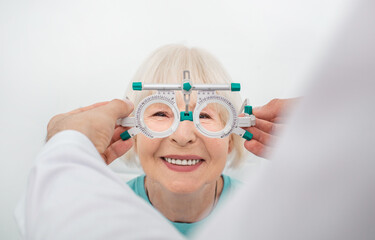 Senior woman wearing optometrist trial frame at ophthalmology clinic. Selection of diopter glasses...