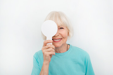 Senior woman having an eye exam with one eye covering using a special tool, on a white background....