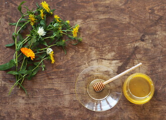 Floral honey idea, organic natural healthy products. Honey and spoon with honey on wooden natural brown background with flowers.