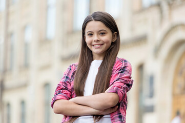 Fototapeta premium Boosting her girls confidence. Confident child keep arms crossed outdoors. Confident look of fashion girl. Casual style. Summer trend. Trendy childrens wear. Kids wardrobe. Be great every day