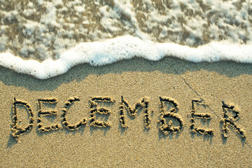 December inscription on the sand beach with the soft wave.