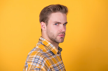 Unshaven guy with stylish hair in casual style yellow background, barbershop