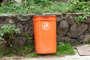Obraz premium Yellow plastic trash can on the street on the sidewalk in the park. Garbage container outside.