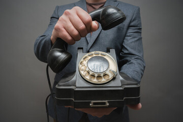 Rotary phone handset in man hand close up on gray background.