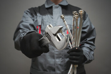 Plumber with adjustable wrench and water hose pipe close up.