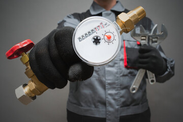 Water meter and adjustable wrench in plumber hands close up.