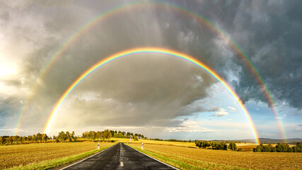 Straße in Richtung doppeltem Regenbogen