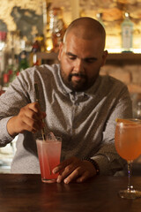 Joven mexicano barman cantinero preparando cocktail en bar discoteca