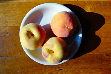Pfirsiche im Sonnenlicht auf weißem Teller