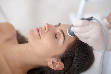 Fototapeta premium Young woman lying down with eyes closed during professional beauty procedures