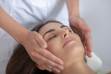 Fototapeta na wymiar Professional massage therapist doing face massage to a woman