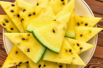 Closeup of fresh yellow watermelon slices on white plate