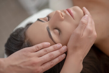 Fototapeta na wymiar Professional massage therapist massaging young womans face