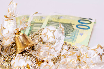 Festive golden garland with sweets, beads in the foreground. Euro 100 bills in the background. Decoration for New Year and Christmas holidays..