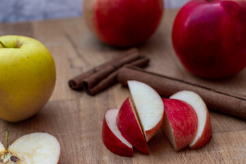 Holzbrett mit Apfelspalten, Äpfel und Zimtstangen
