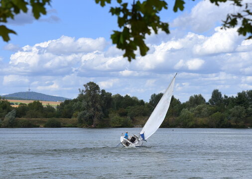 Schr&auml;g im Wind liegendes Segelboot  vor blauem Himmel mit wei&szlig;en Wolken 