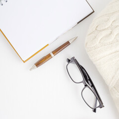 Workspace with pen, notebook, coffee cup, glasses.