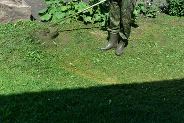 The process of mowing grass with a gasoline trimmer in the garden