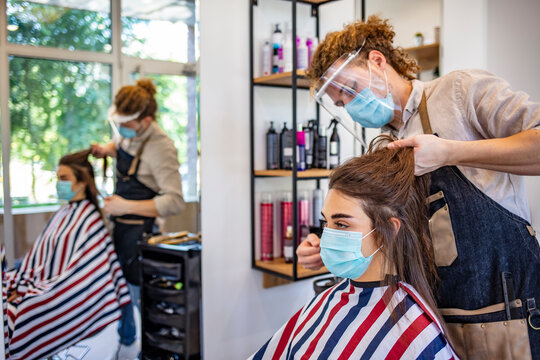Adult woman at hairdresser wearing protective mask due to coronavirus pandemic. Woman in protective medical mask and hairdresser. Hairdressing salon opened! Covid-19, coronavirus .