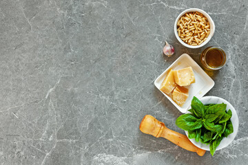 Ingredients for pesto. Top view of basil, pine nuts, garlic, parmesan and olive oil on gray stone background