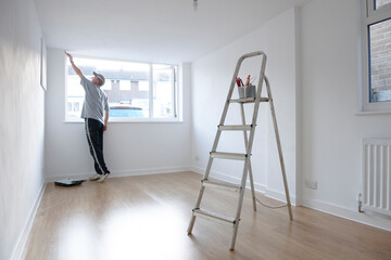 man decorating a room with ladder and paint pot in foreground