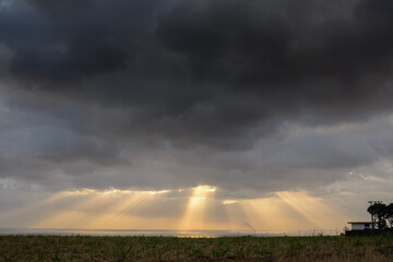 storm clouds over the field with sunrays