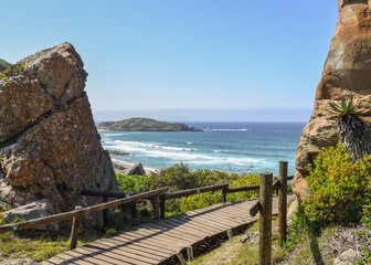 A wooden walkway that passes through the rocks towards the sea, in Robberg Nature Reserve, South Africa.