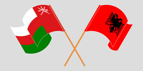 Crossed and waving flags of Albania and Oman