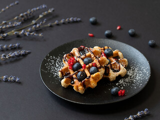 Homemade waffles with blueberries on the black background. Selective focus.
