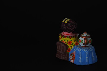 Funny figures. Toys made of plaster and ceramic. Isolated, close-up, black background.