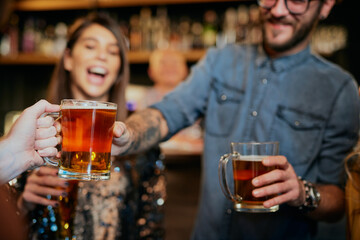 Closeup of man passing beer to his friend while standing in a pub.