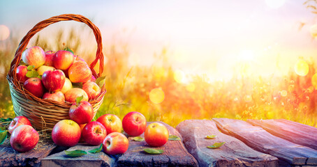 Obraz na płótnie Canvas Red Apples In Basket On Aged Table With Defocused Sunset In Background - Fall And Harvest Concept 