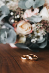 Golden weddings rings in front of a bridal bouquet