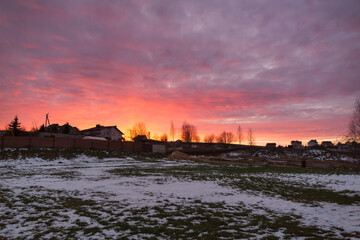 Fototapeta premium a flat piece of land put up for sale at auction in winter with a beautiful pink sunset
